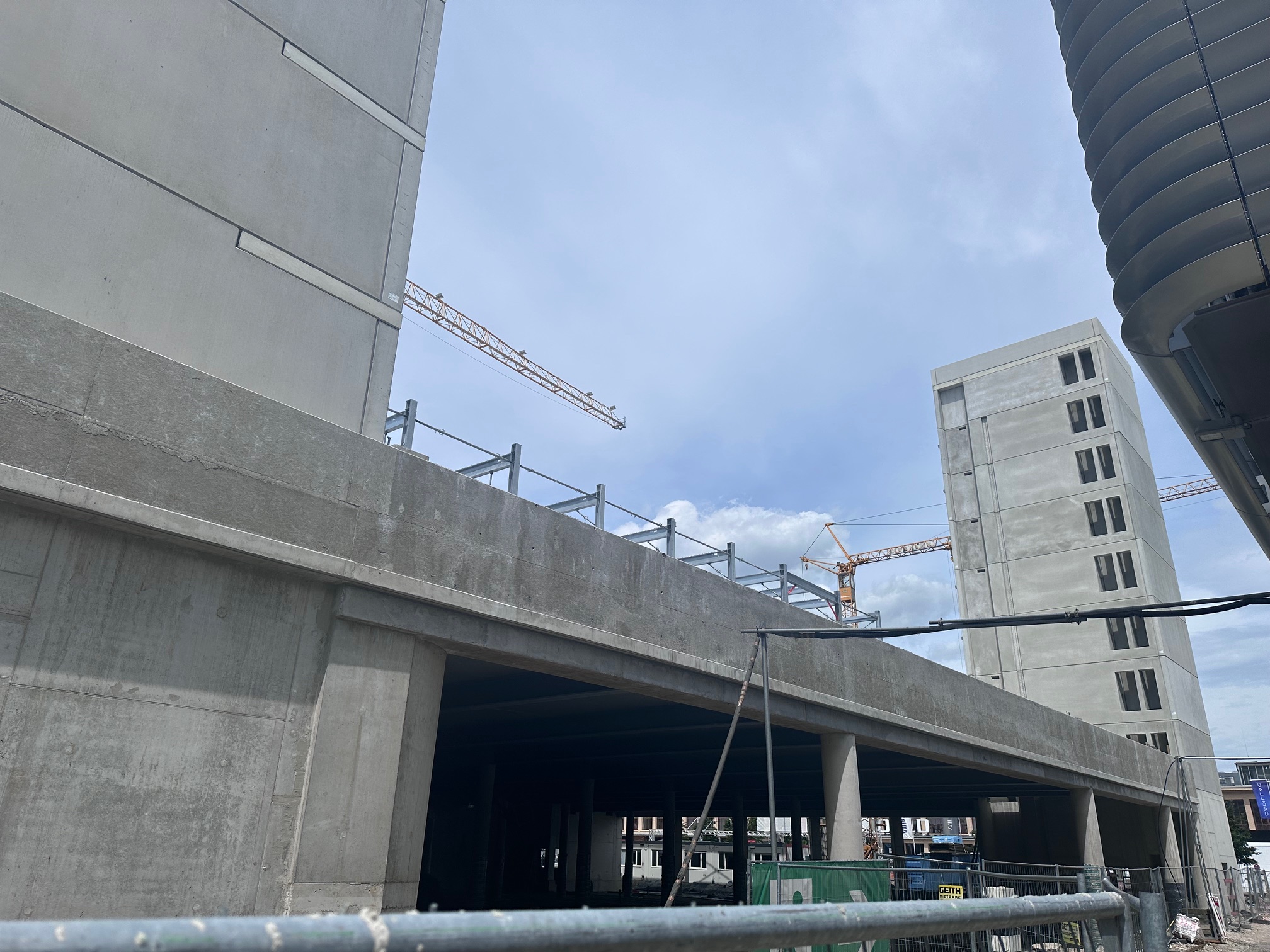 Betonparkhaus im Rohbau mit Treppenturm und Baukränen, Parkhaus Motorworld München