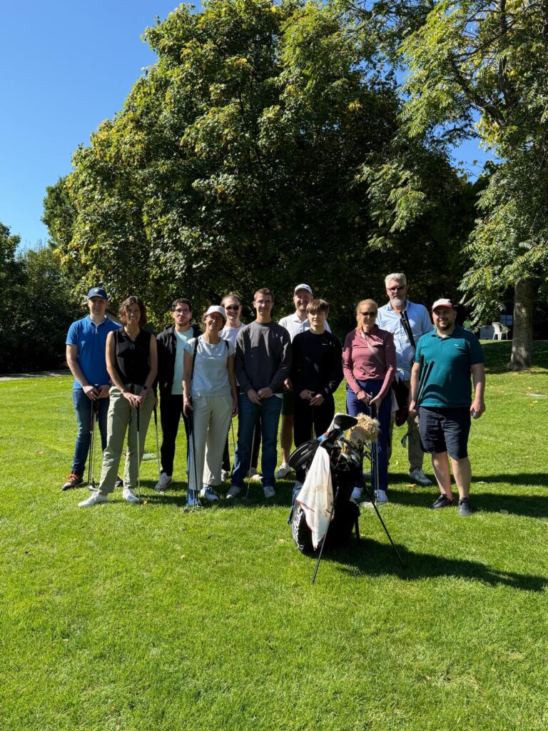 Gruppenfoto auf einer Wiese beim Betriebsausflug auf dem Golfplatz