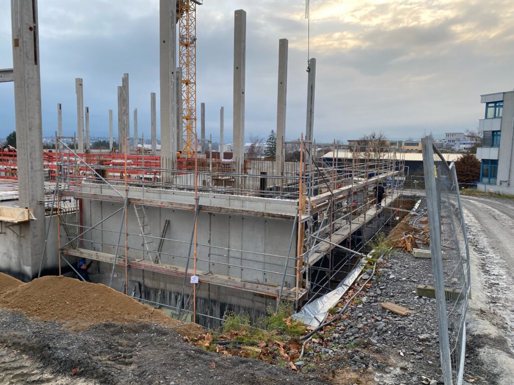 Rohbau der Lagerhalle in Öhringen mit Betonwand, Gerüst und hohen Fertigteilstützen