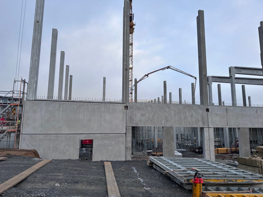 Betonwand und Fertigteilstützen mit Betonpumpe auf der Baustelle der Lagerhalle in Öhringen