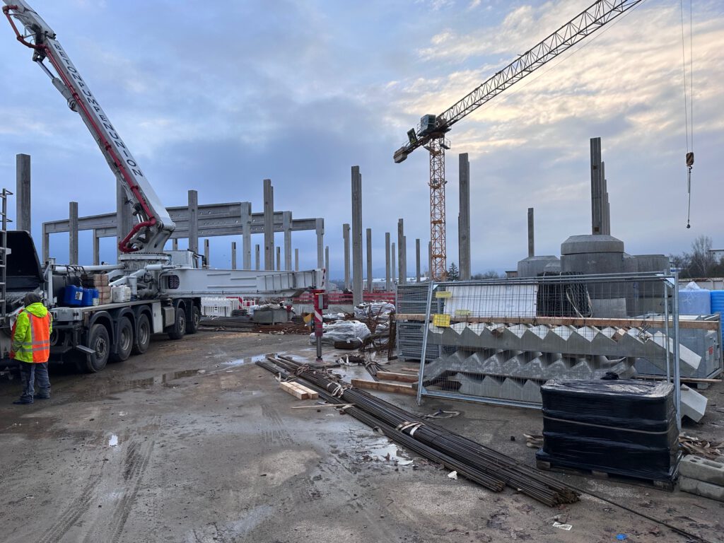 Baustelle der Lagerhalle in Öhringen mit Betonstützen, Autobetonpumpe und Turmdrehkran