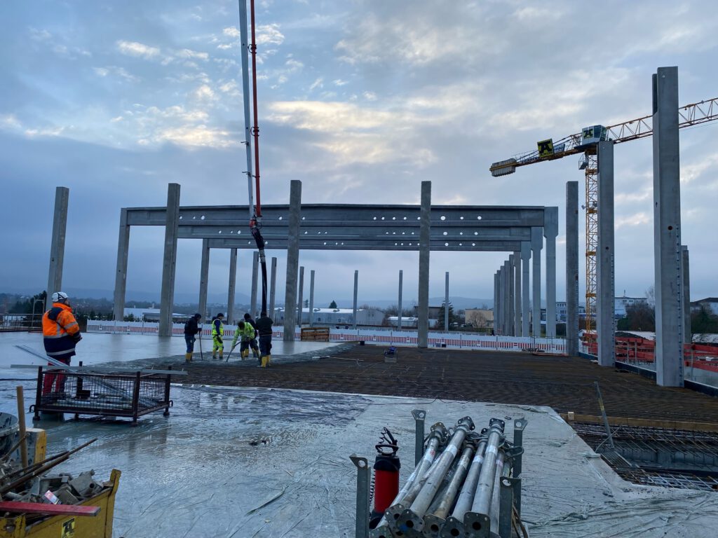 Betonierarbeiten auf der Decke zwischen Fertigteilstützen mit Betonpumpe, Lagerhalle Öhringen
