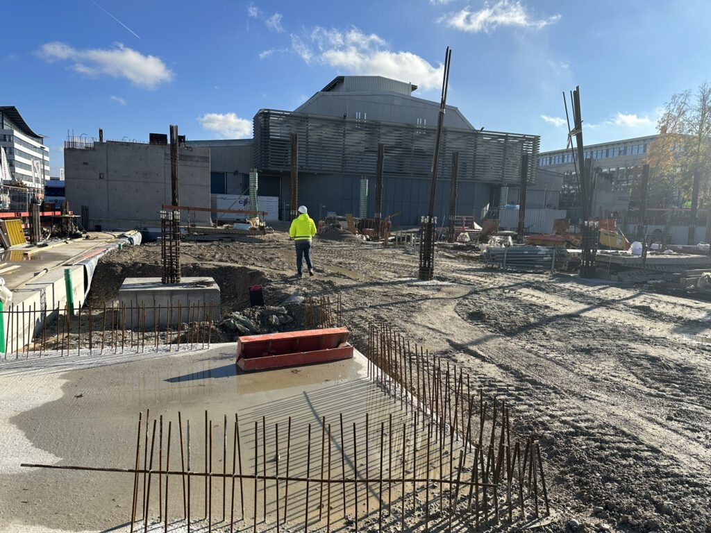 Baustelle mit Bewehrungsstäben, Betonplatte und Person in Warnweste, Parkhaus Motorworld München