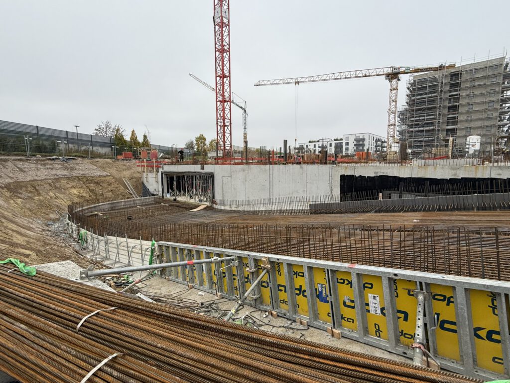 Bewehrung und Schalung einer gebogenen Wand in der Baugrube mit Kränen, Candis II Regensburg