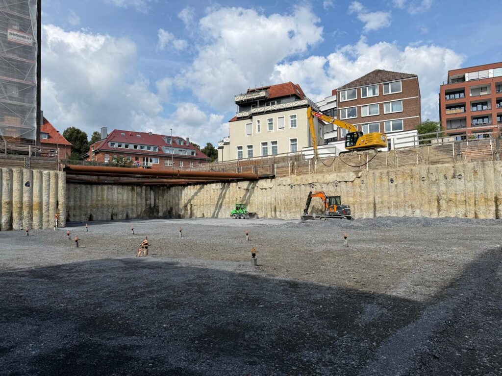 Bohrpfahlwand mit Stahlsteifen und Baggern auf der Sohle der Baugrube