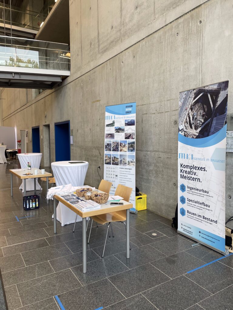 MKI-Messestand in der Halle mit zwei Roll-ups, Tisch mit Broschüren und Stehtisch