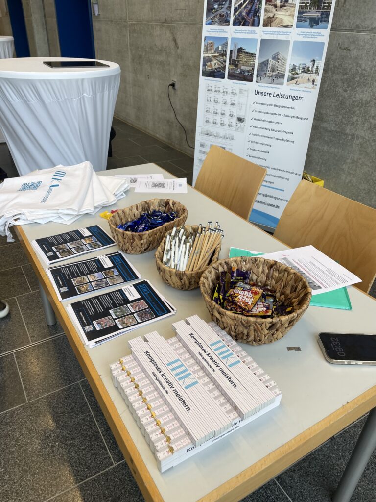 Tisch am MKI-Stand mit Broschüren, Projektkarten, Kugelschreibern und Körben mit Süßigkeiten